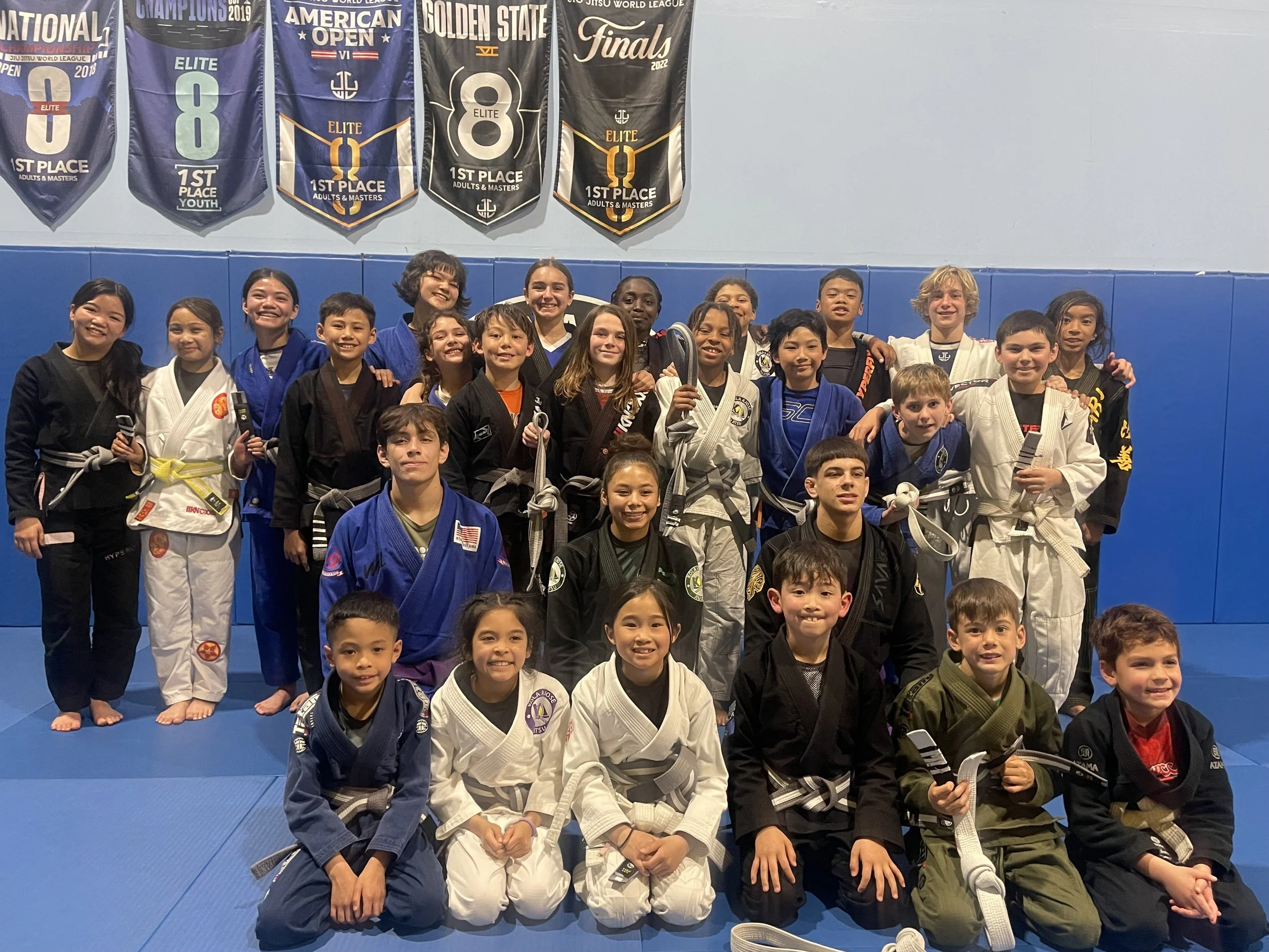 Youth Jiu-Jitsu students beneath academy championship banners